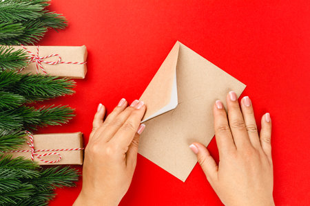woman hands send letter with Christmas greetings in frame of fir branches and bundles of cinnamon