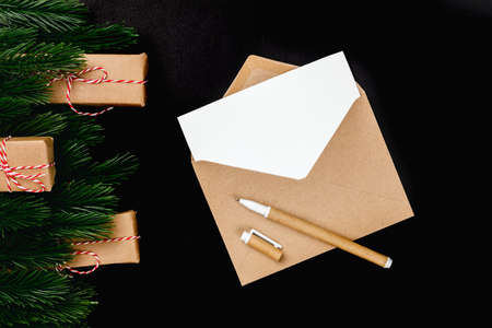 christmas greeting card with craft writing materials on black isolated background with fir branches and gift boxesの写真素材