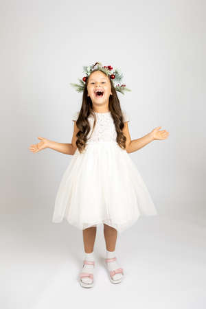 full-length portrait of laughing, joyful woman in elegant white dress and Christmas wreath, isolated on white background with copy spaceの写真素材
