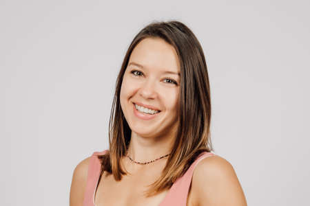 Portrait of brunette on isolated gray background. Young happy woman poses in studio, turning...
