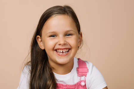 Close-up face kid with bright shining eyes and excited happy smile with teeth looking at camera...