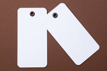Cardboard blank white colored tags of rectangle shape with tiny holes in upper part for clothes in...