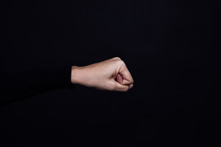 Caucasian person clenched fist isolated on black background. Copy space. Domestic violence. Physical and psychological abuse, relative aggression, gaslightingの写真素材