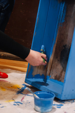 Woman hand with brush painting inner part of antique closet drawer made of wood in blue. Reuse of old things. Sustainable eco-friendly actions for planet futureの写真素材
