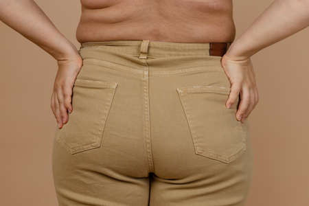 Closeup of lady back of large waist with love handles, sides having jeans on. Body positive. Accepting who you are. Tight clothes. Need for wardrobe changeの写真素材