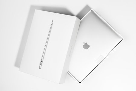 Saratov, Russia - February 26, 2022: demonstration of new Macbook Air 13 inch with M1 processor in stylish packaging flat lay, white background. Advertising of modern technology and portable deviceのeditorial素材