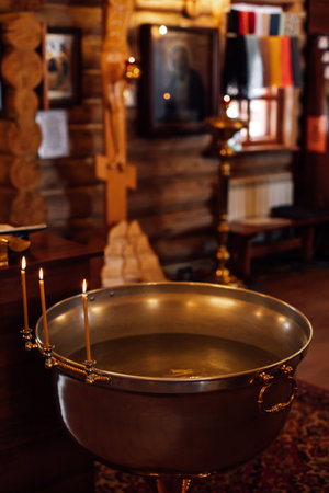 Traditional font decorated with candlesticks with burning candles filled with water is ready for...
