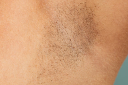 Person with hairy underarms closeup, free copy space, skin background. Arm with armpit hair. Female beauty trend, freedom, sensitive skin, growing body hair, feminism, body positive, naturalnessの写真素材