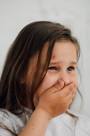 portrait of little sad bruised girl with long dark hair covering mouth with hand. Protest against abuse.の写真素材