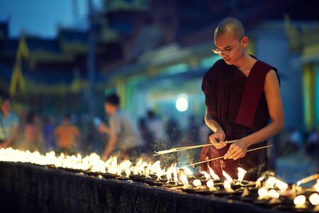 Portrait of buddhist monk lights a candlesの写真素材