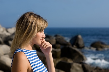Attractive thoughtful girl on a beautiful rocky beach by the sea.の写真素材