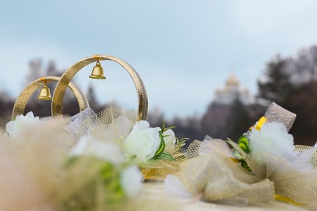 Wedding rings and flowers (decorative) on the roof of the car. In the background the church council....