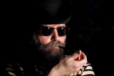 Man dressed as a pirate in tricorn hat smoking a pipe.の写真素材