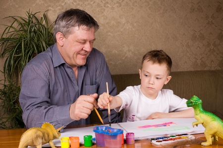 His grandfather teaches his grandson drawing paint.の写真素材