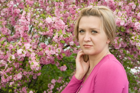 Pretty blonde young woman on the background of the cherry blossoms. Spring.の写真素材