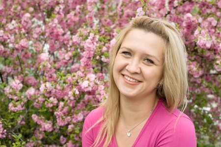 Pretty blonde young woman on the background of the cherry blossoms. Spring.の写真素材