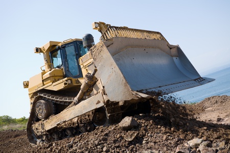 The bulldozer on a building site.On a background the sea.
