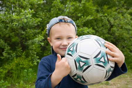 The little boy holds a football in hands.の写真素材