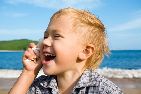 Little boy holds a shell in a hand.
