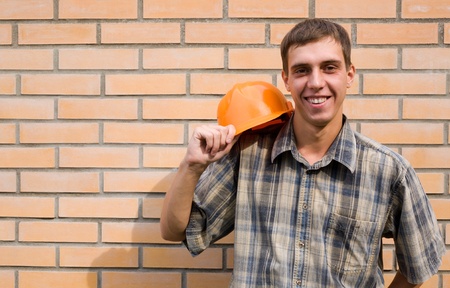 Bricklayer on a background of a new brick wall.の写真素材