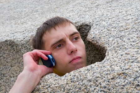 Young man speaks by mobile. Stone.の写真素材