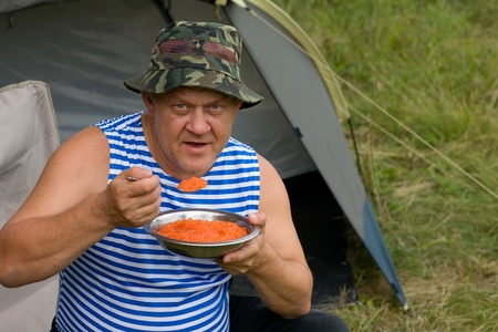 Middle-aged man eating freshly prepared (salted) red caviar in field conditions. Fun ;) Russia.の写真素材