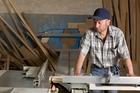 Carpenter working on woodworking machines in carpentry shop.の写真素材
