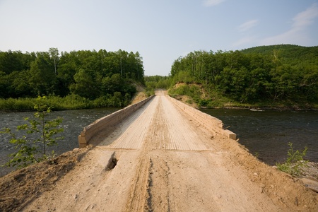 Wooden bridge across the river for vehicles. Russia. Remote area.
