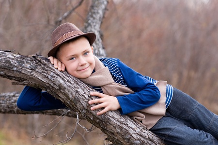 Smiling boy lying on a tree trunk. Autumn.の写真素材
