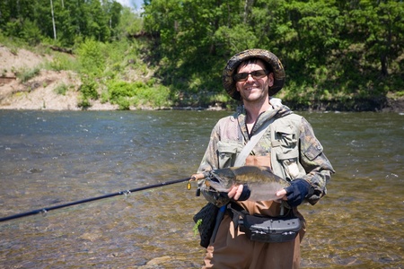 Joyful fisherman keeps caught masu salmon (or cherry salmon). Russia. Primorskiy  kray.の写真素材