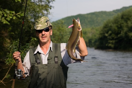 Happy fisherman caught a salmon (pink salmon) on the Riverの写真素材