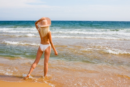 Slim blonde girl wearing a hat at the beachの写真素材