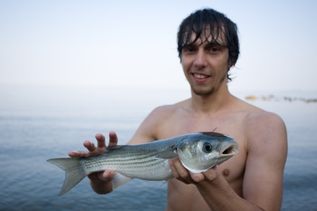 Fisher holds a freshly caught sea mullet  Sea of Japan の写真素材