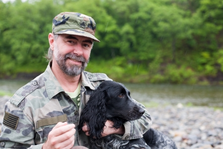 Middle aged man with a dog (Russian Hunting Spaniel), a uniformed sergeant US Army. At the river. Rain. の写真素材