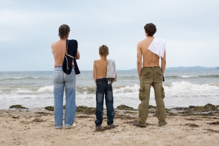 Father, son and grandson looking at the ocean.の写真素材