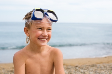 Joyful boy on the beach in a mask for scuba diving.の写真素材