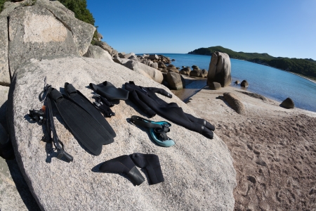 Wetsuit and a gun for underwater hunting lie on the stone. Fish-eye lens.の写真素材