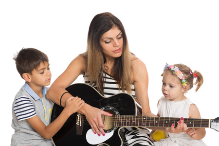 Young mother playing guitar for their children.の写真素材