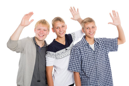 Cheerful group of young boys with their hands raised in greeting. Two of the boys twin brothers.の写真素材
