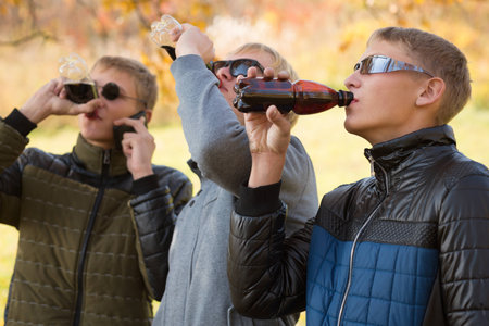 Young guys drink beverages from bottles in the park. の写真素材