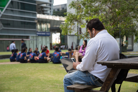 SINGAPORE - CIRCA FEBRUARY, 2015: Man uses a tablet computer while in the Central Business District of Singapore, close to the station Raffle Place.のeditorial素材