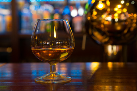 Glass with an alcoholic drink is on the bar rackの写真素材