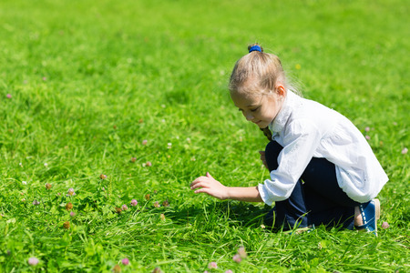 Girl catching a grasshopper in the grassの写真素材