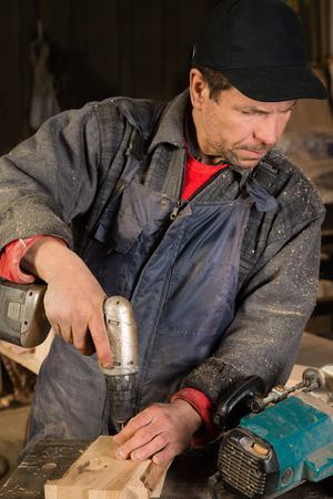 Carpenter working with a drill in the carpentry workshop. Focus on tool.の写真素材