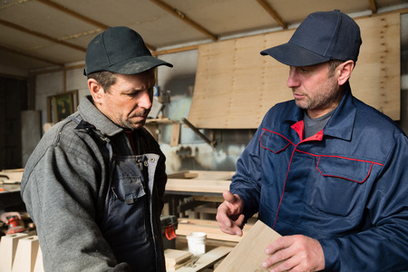 Supervisor and worker to discuss the process of making wood products for furniture.