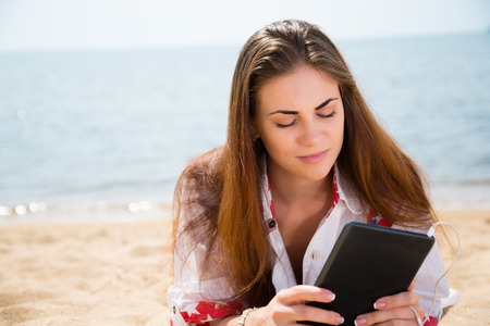 Young woman resting with tablet computer on the beach
