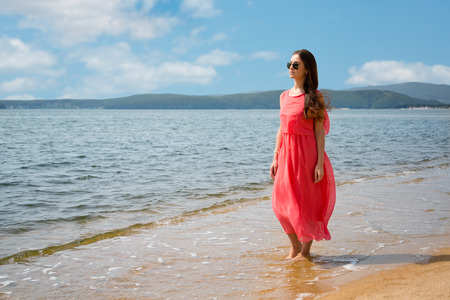 Beautiful young woman stands on the sandy sea shoreの写真素材