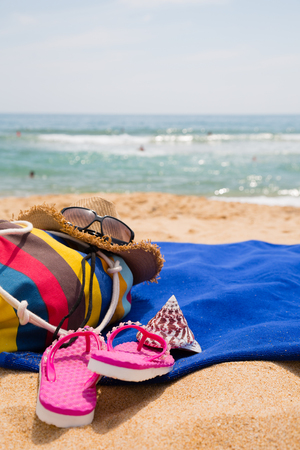 Hat, sunglasses, towel and other items on a tropical beachの写真素材