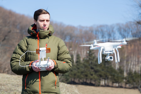 Young man controls the drone in open terrain