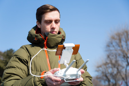 Young man holding a controller and controls the droneの写真素材